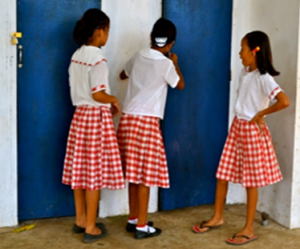 <p>Three school girls peaking in a school latrine in the Philippines.</p>
